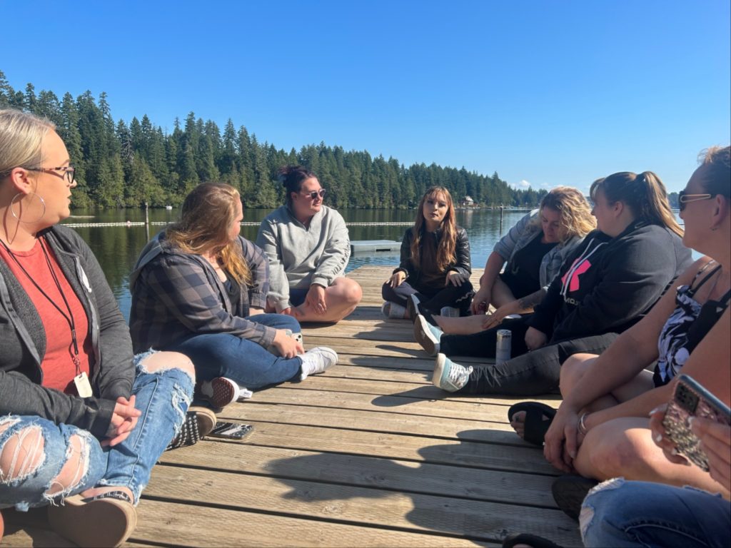 a group of people sitting cross legged on a wooden dock