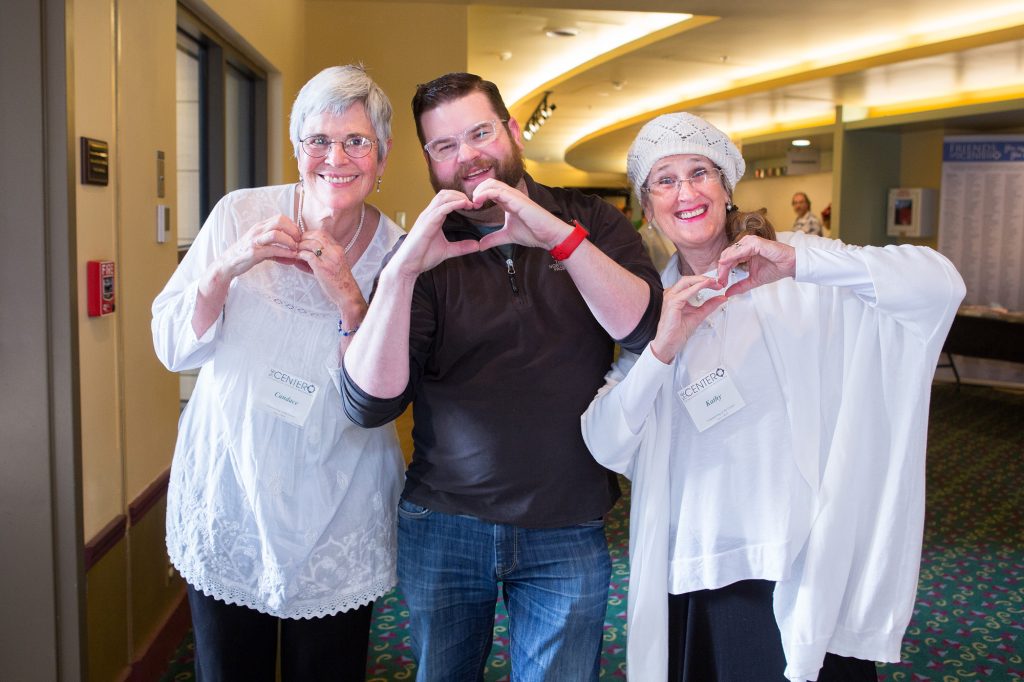 Three people standing with their hands making heart shapes