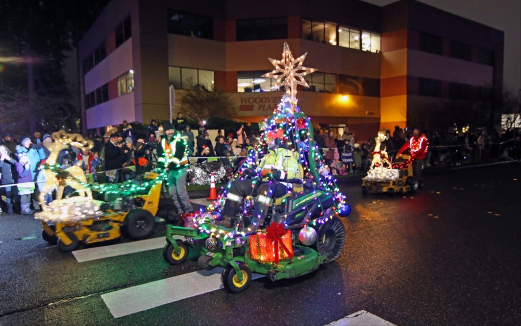 People with riding and push lawn mowers decked out in Christmas lights for the Lacey Lighted Parade