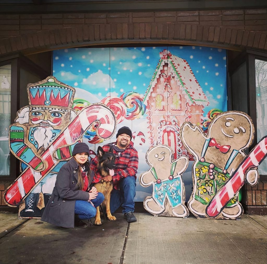 people posing for a photo with a gingerbread house painting