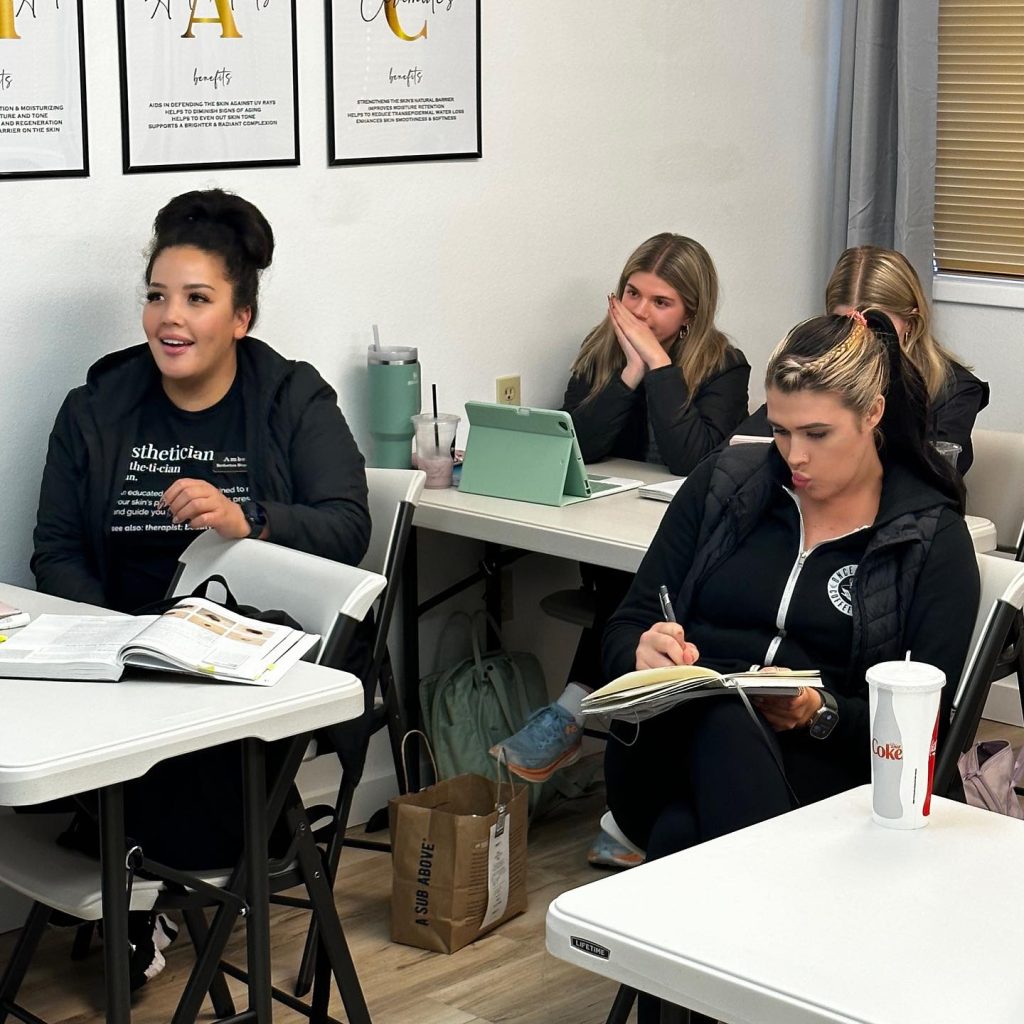 four woman sit at tables with books, notes and an iPad in front of them