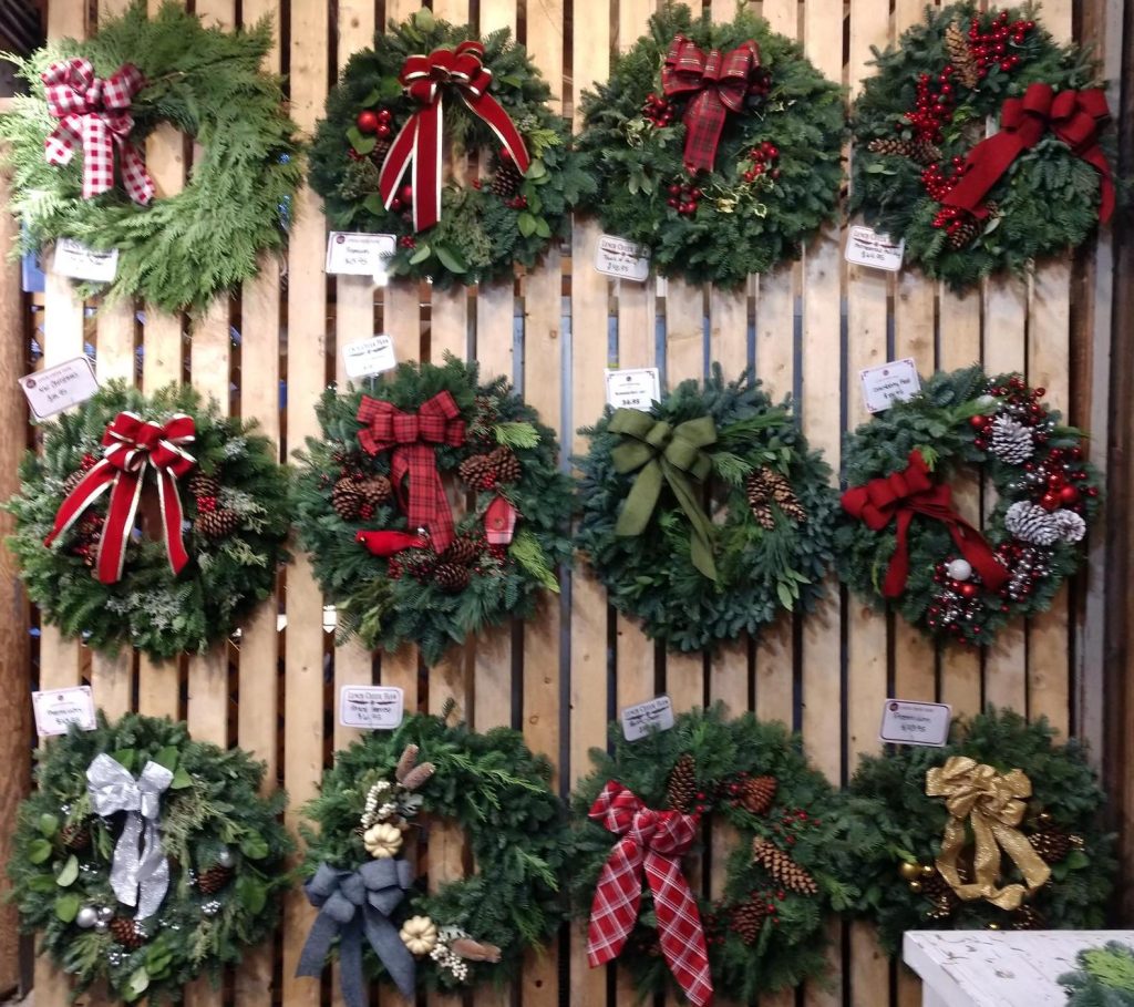 rows of wreaths with red bows hanging on hooks