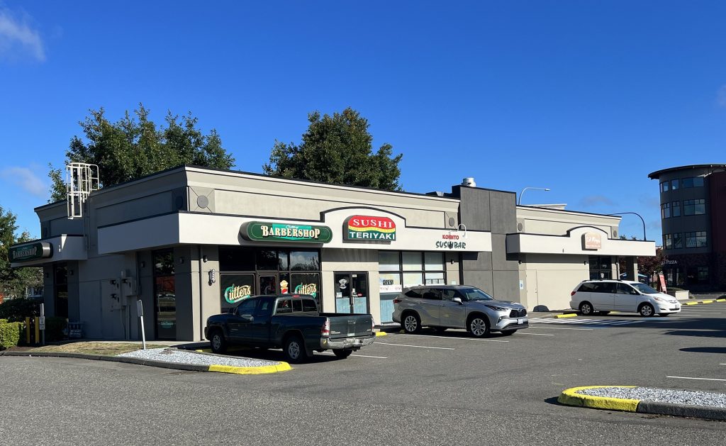 strip mall-type buildings at the Port of Olympia with signs that say, 'barbershop, sushi teriyaki and sushi bar'