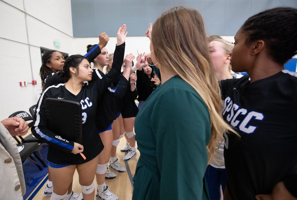 SPSCC women's volleyball team in a locker room huddle