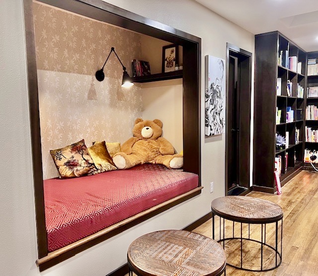 a book nook in a home with a red cushion a teddy bear and pillows