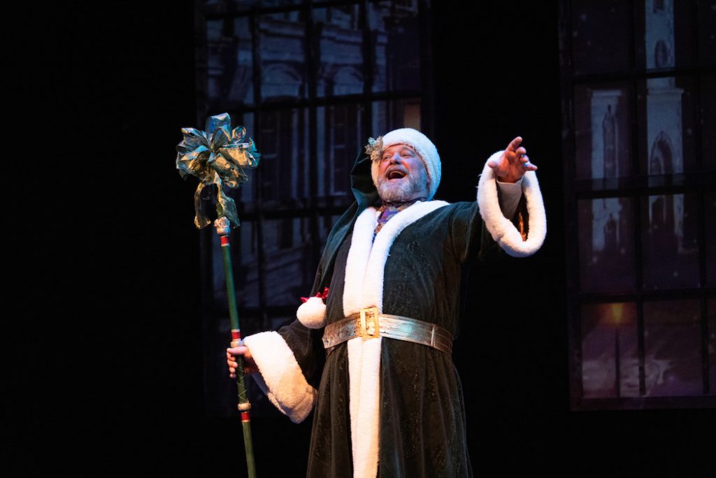 an actor dressed as the Ghost of Christmas Present on stage