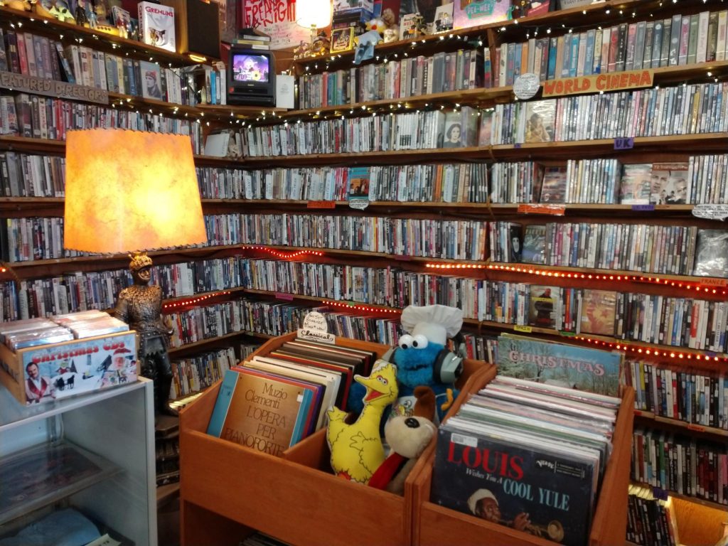 bookshelves full of movies and large wooden bins with records