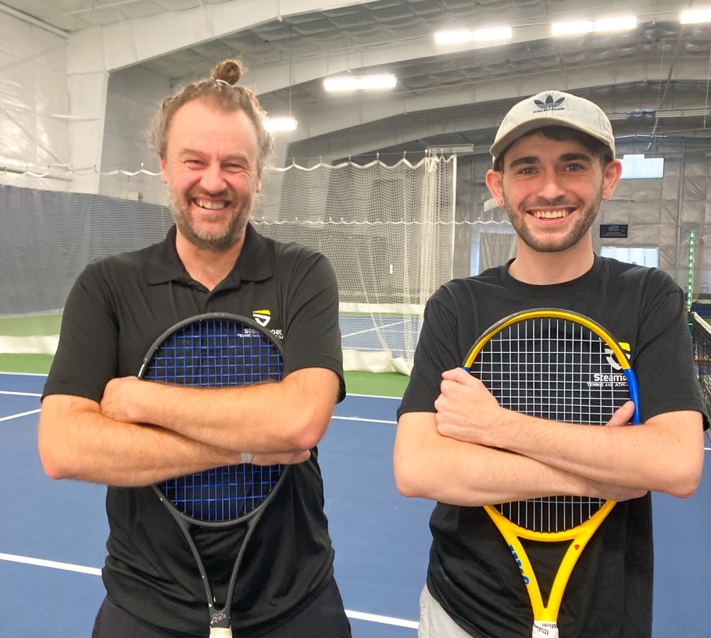 Eric and Bennett hugging tennis rackets and smiling at the camera