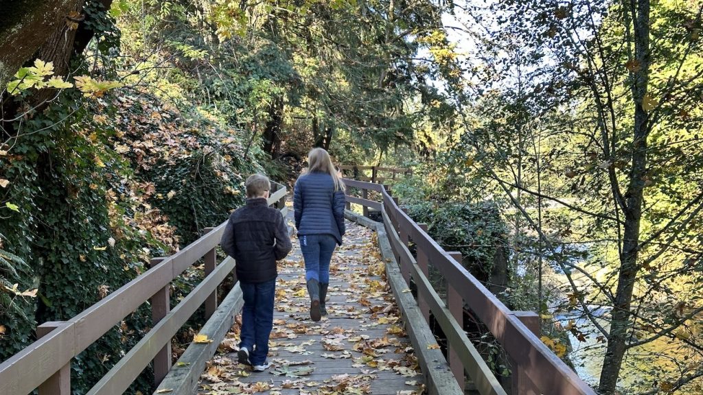 two kids walking up a long wooden walking bridge
