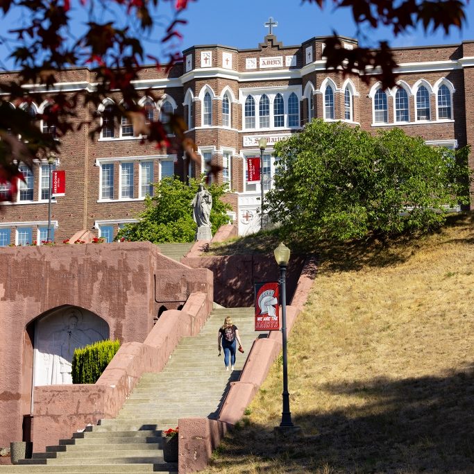 a person walks up the steep long concrete stairs in front of Saint Martin's University