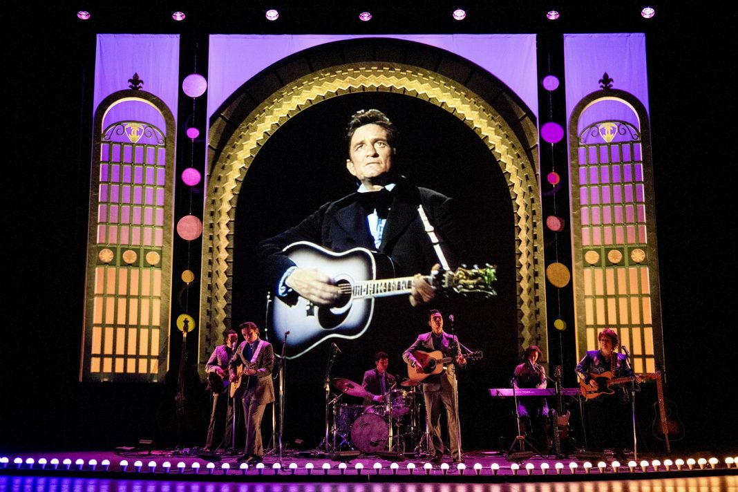 Stage with band performing with photo of Johnny Cash