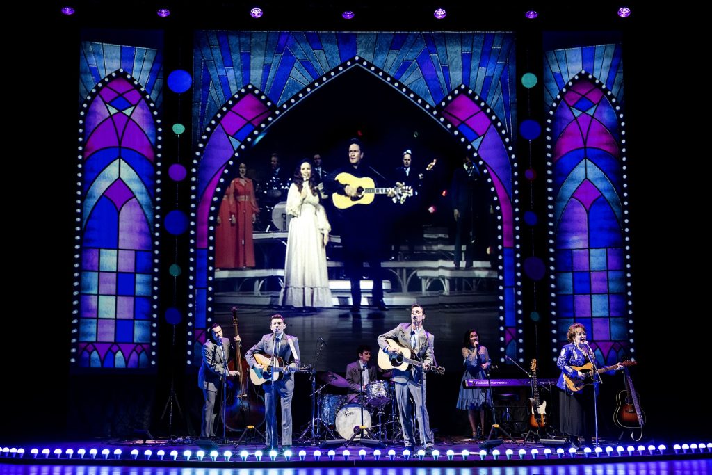 Stage with band performing with photo of June Carter and Johnny Cash 
