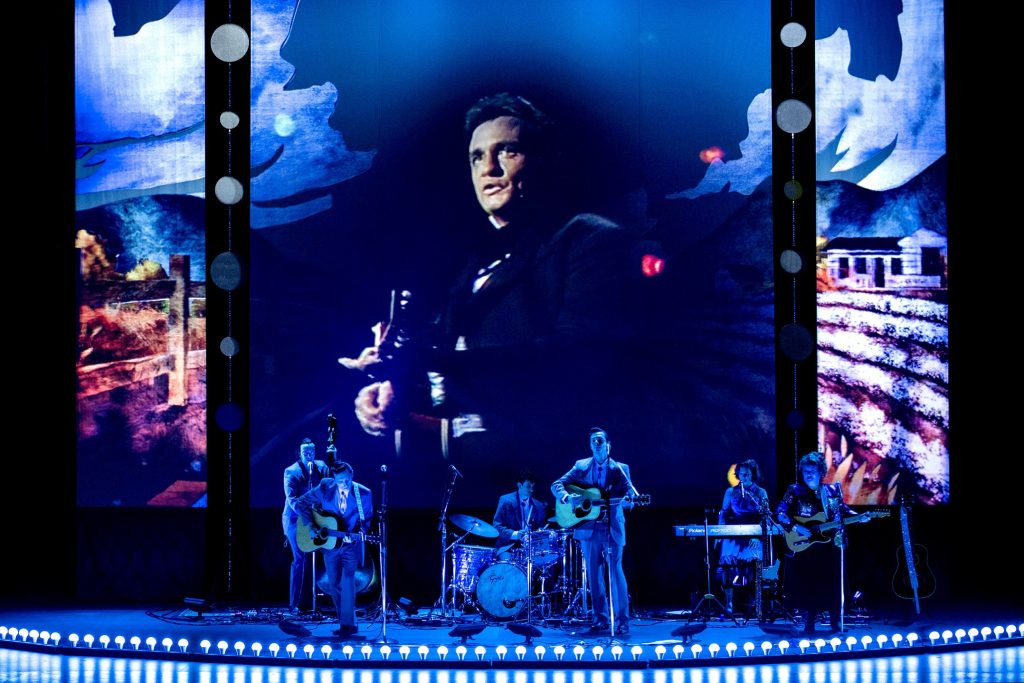 Stage with band performing with photo of Johnny Cash