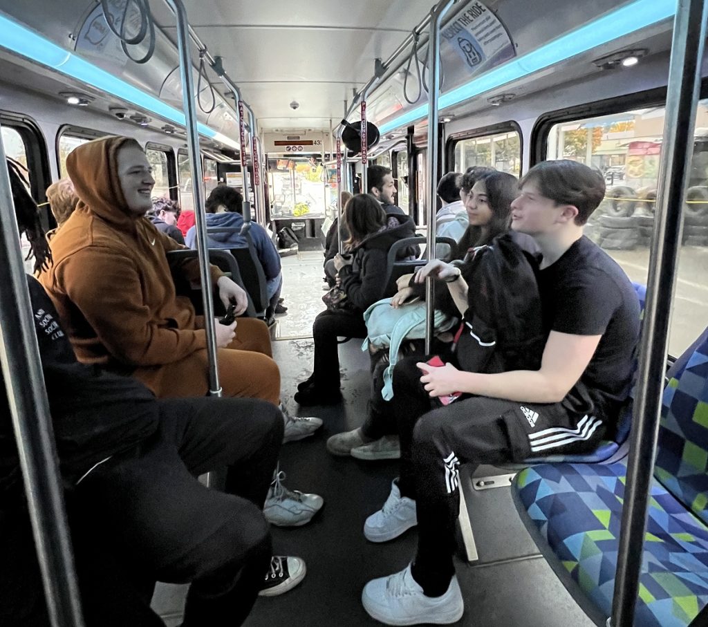 high school students sitting on a city bus