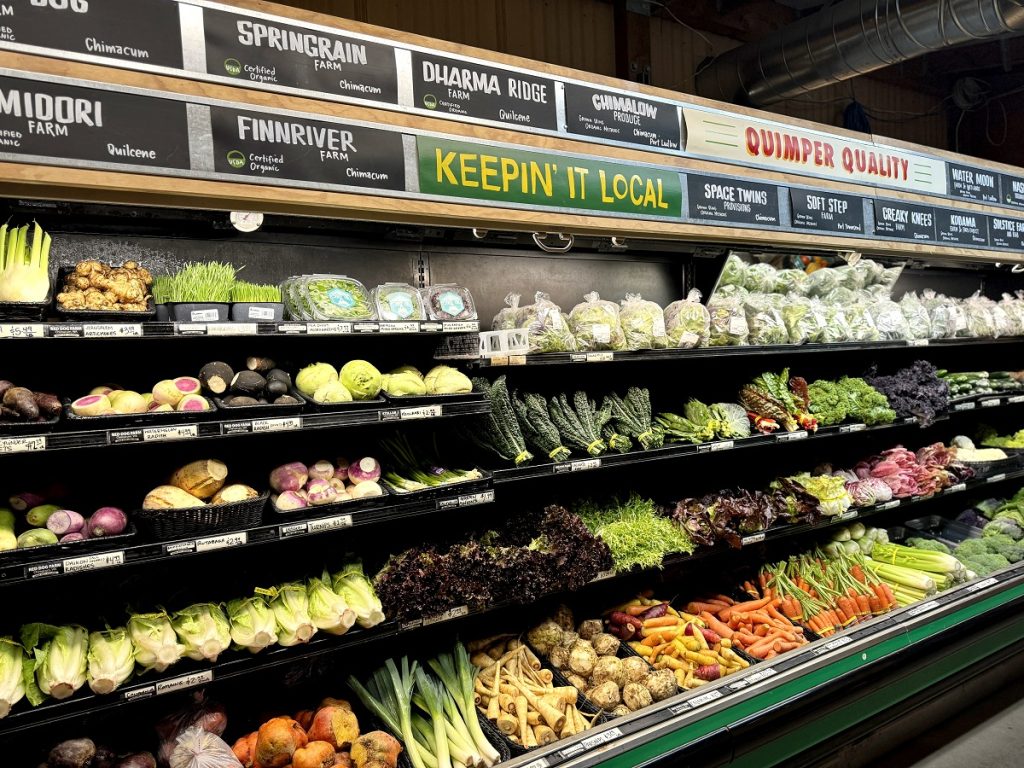 a grocery store produce department with tons of vegetables on display on black shelves