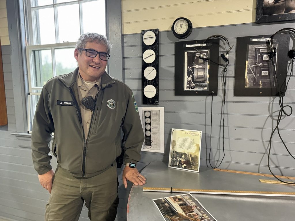 Ranger Aaron Terada standing by a wall with historic photos on it