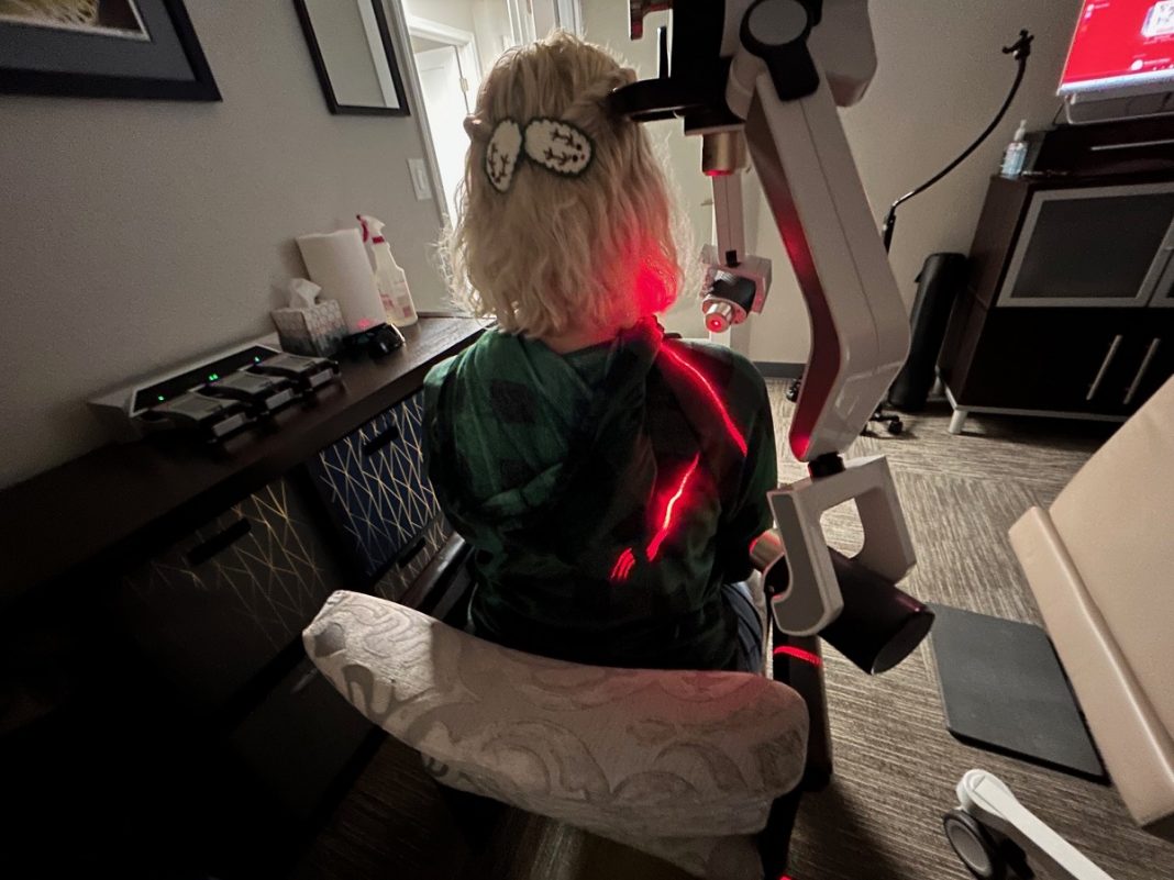 woman sitting in a chair getting cold laser treatment on her shoulder