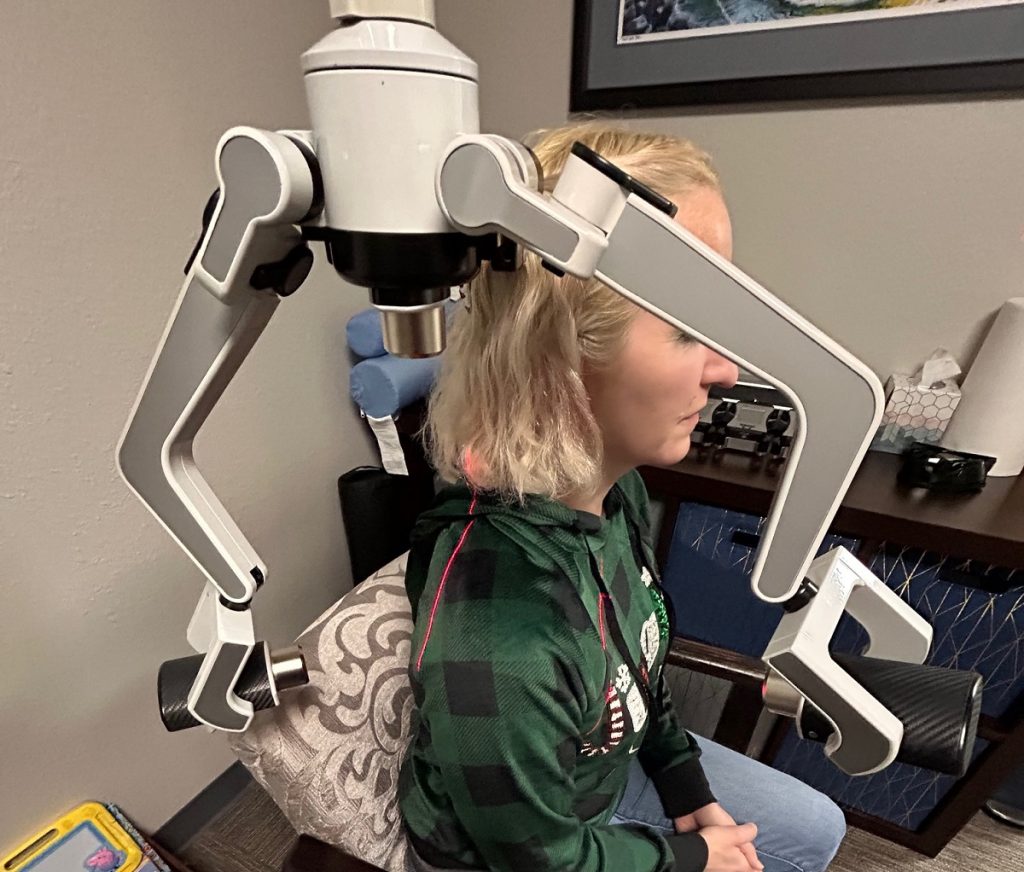 woman sitting in a chair getting cold laser treatment on her shoulder