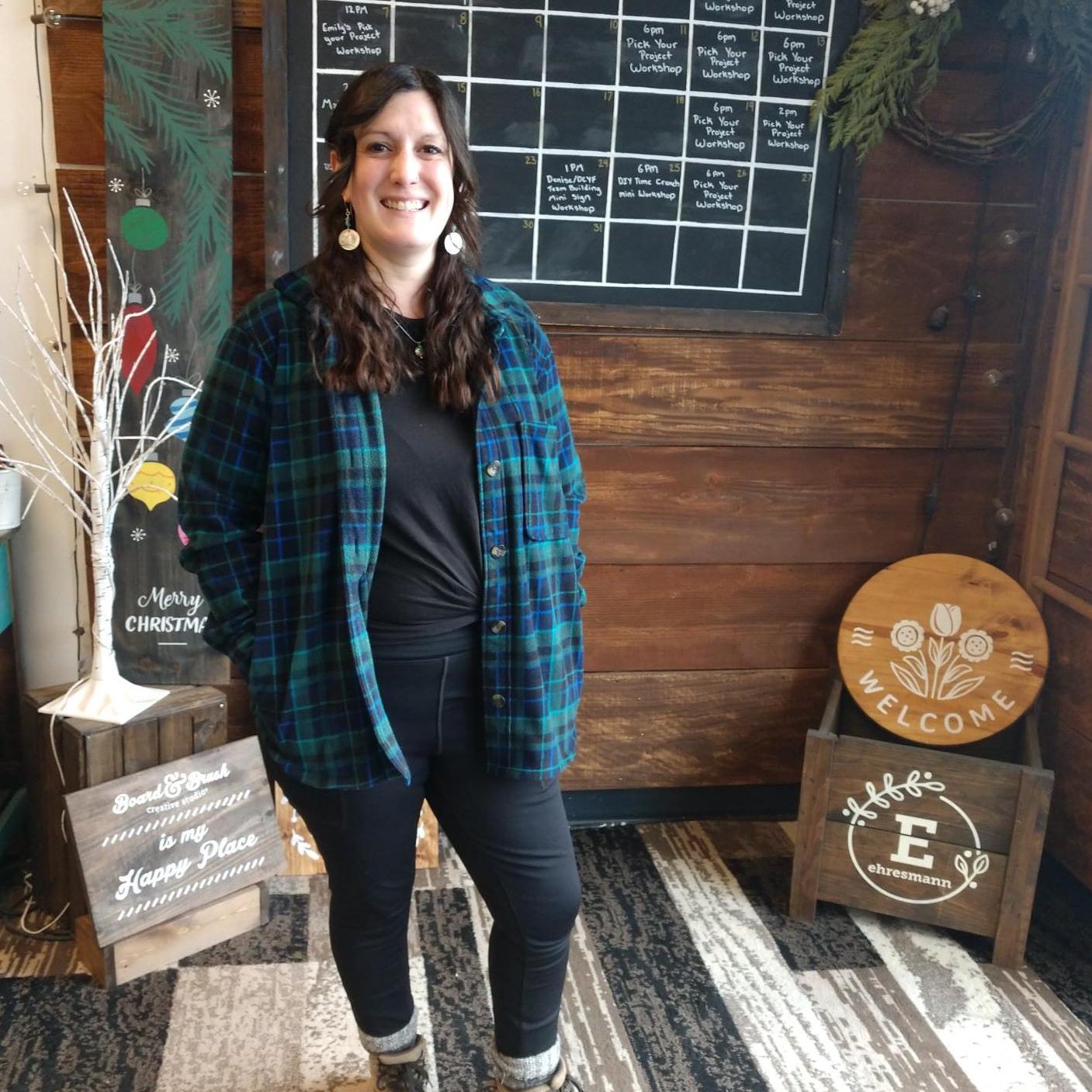 Erika Gulliford standing in Board & Brush with a chalkboard calendar behind her that says 'January'