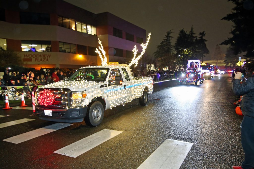 pick up covered in christmas lights with a red ball on the grill and antlers on the roof in a christmas parade