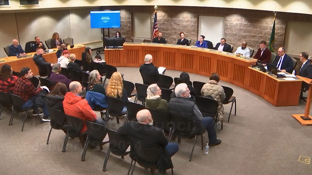 Lacey council meeting with people sitting in chairs facing the council members on a podium