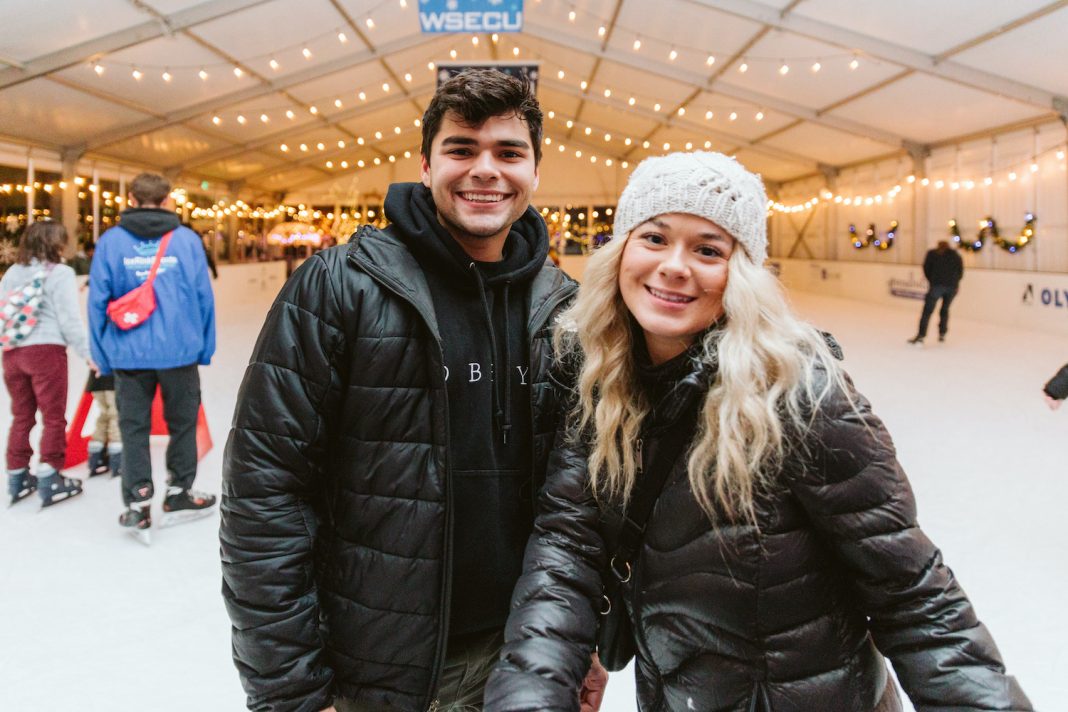 a man and woman pose for a picture inside the Oly on Ice rink