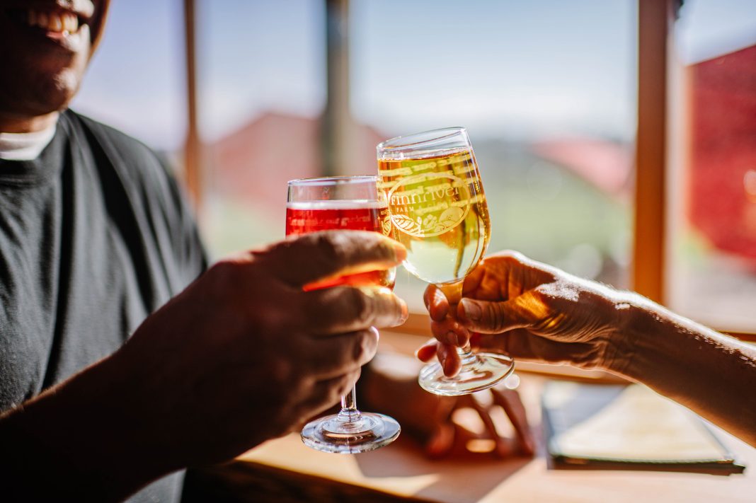 two hands toasting with glasses that say "Finnriver" on them