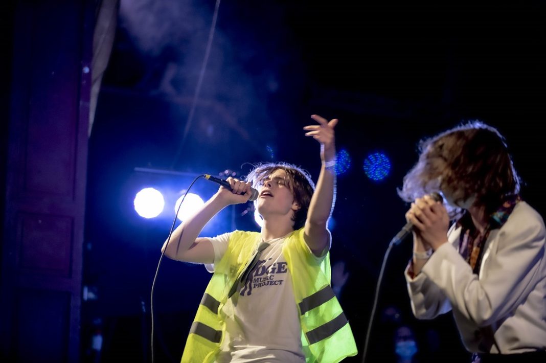 Two young men on stage singing into hand-held microphones