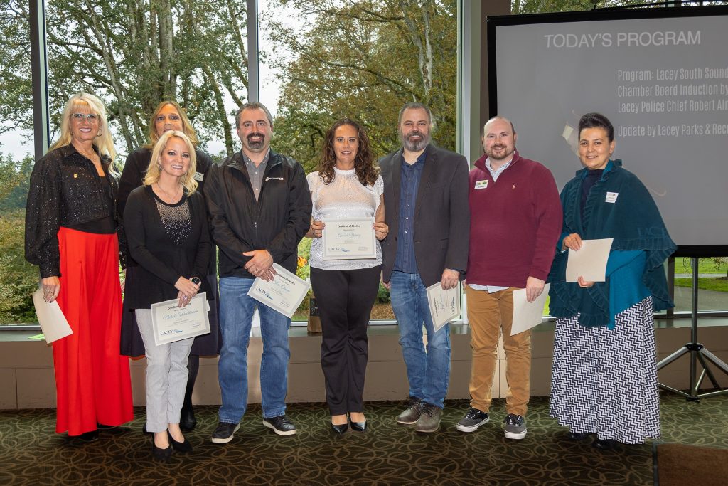 8 new members of the Lacey South Sound board stand with certificates in front of a screen that says 'Today's Program, Lacey South Sound Chamber board induction'