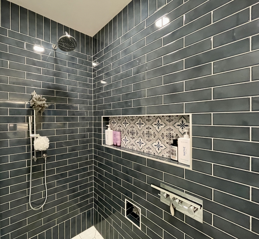 A shower with grey subway tile
