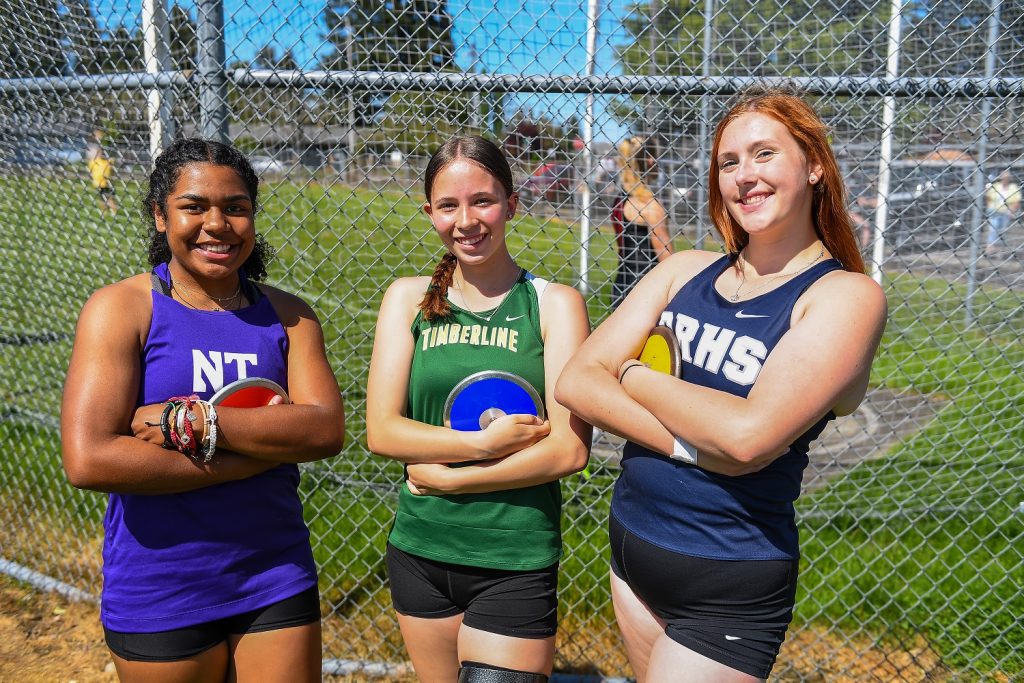 Three girls in track uniforms pose with arms folded on their chests.