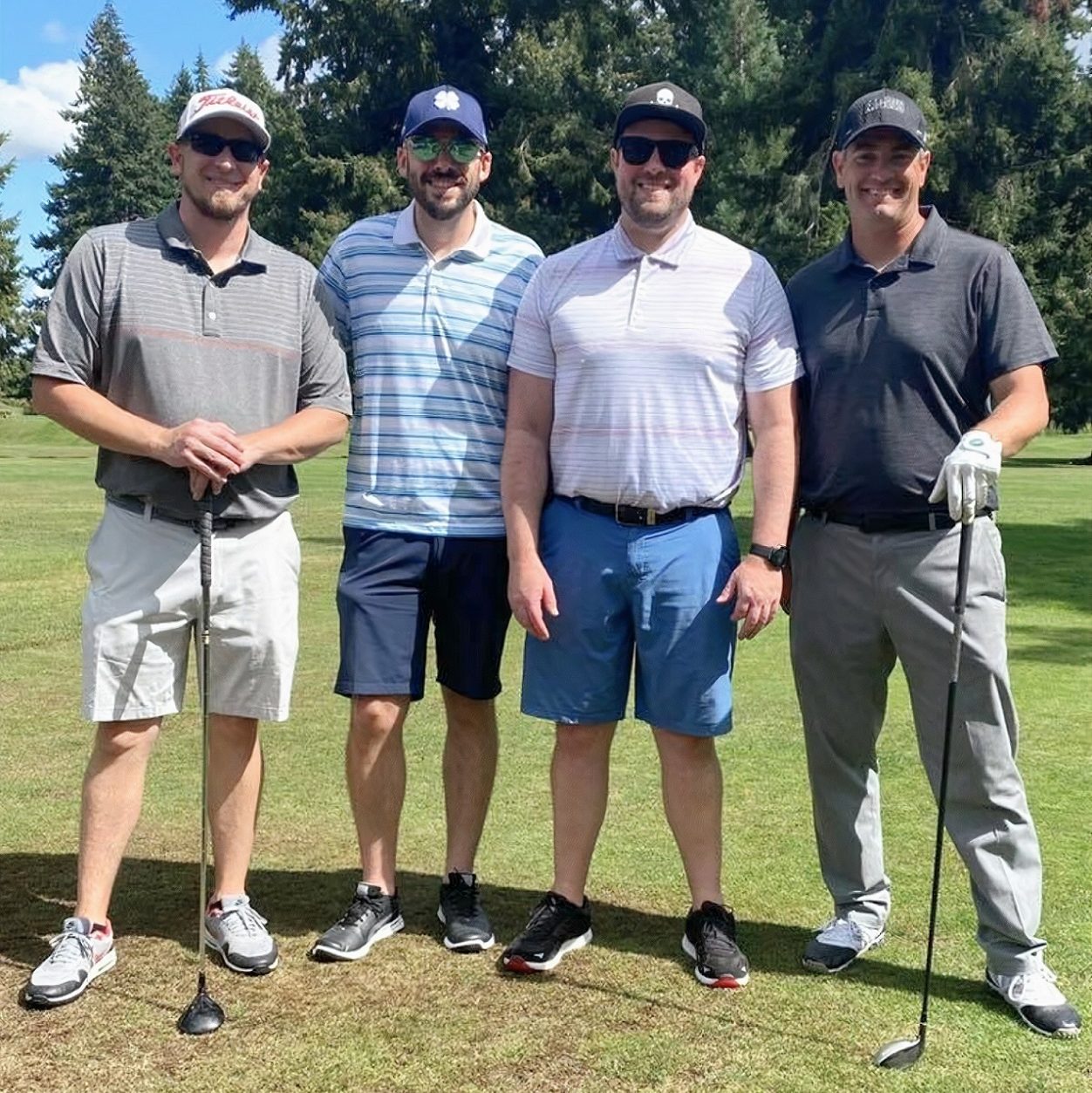 four men standing in a row on a golf course