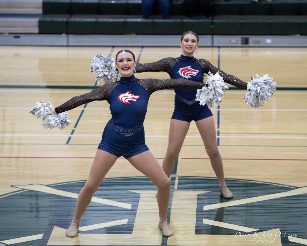 Two cheerleaders performing on a basketball court