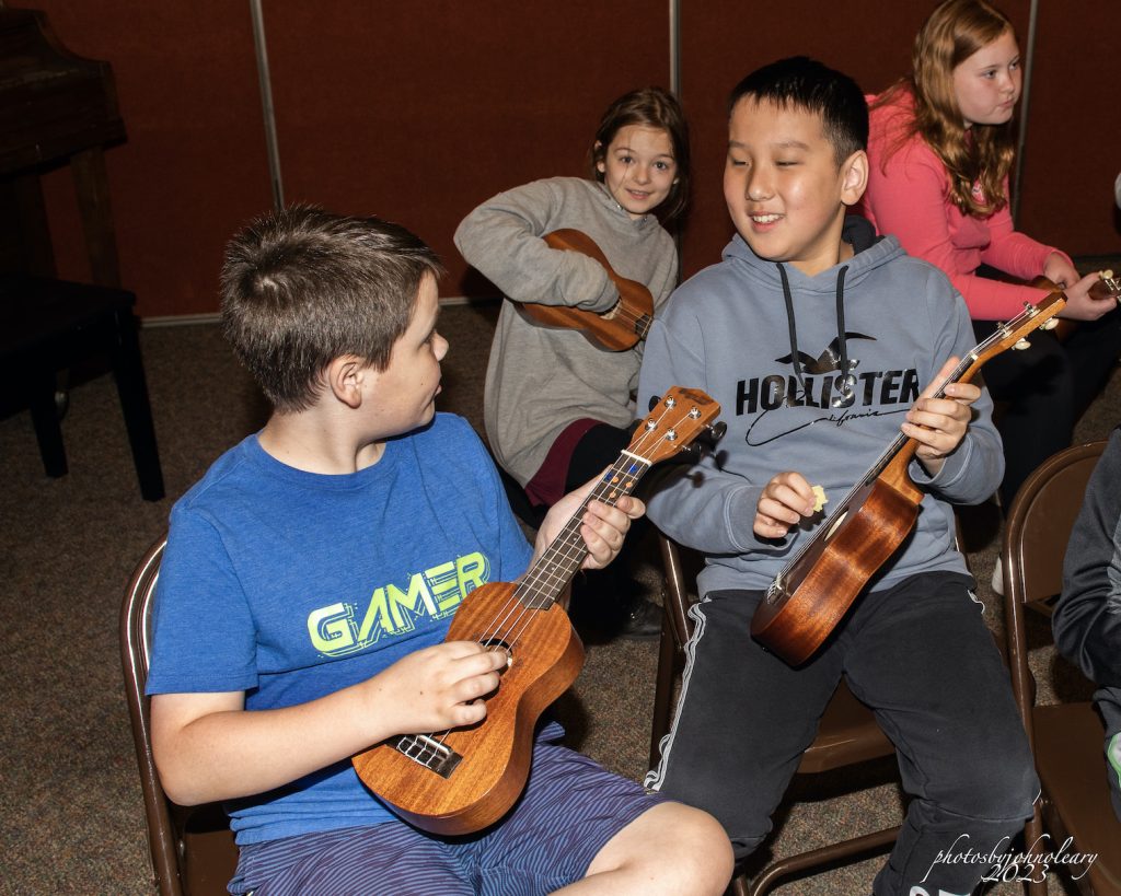 grade school students playing on string instruments