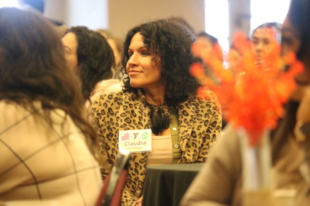 a woman sitting in a crowd is smiling