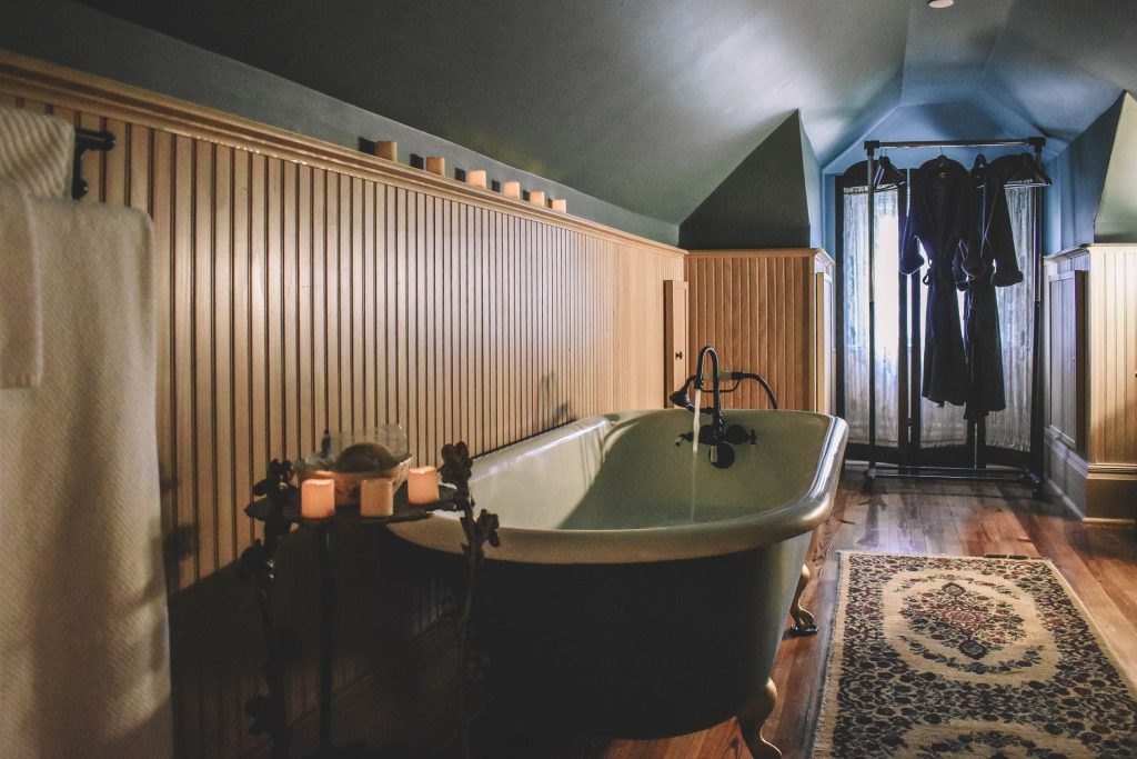a wood-paneled bathroom with a claw tub being filled with water