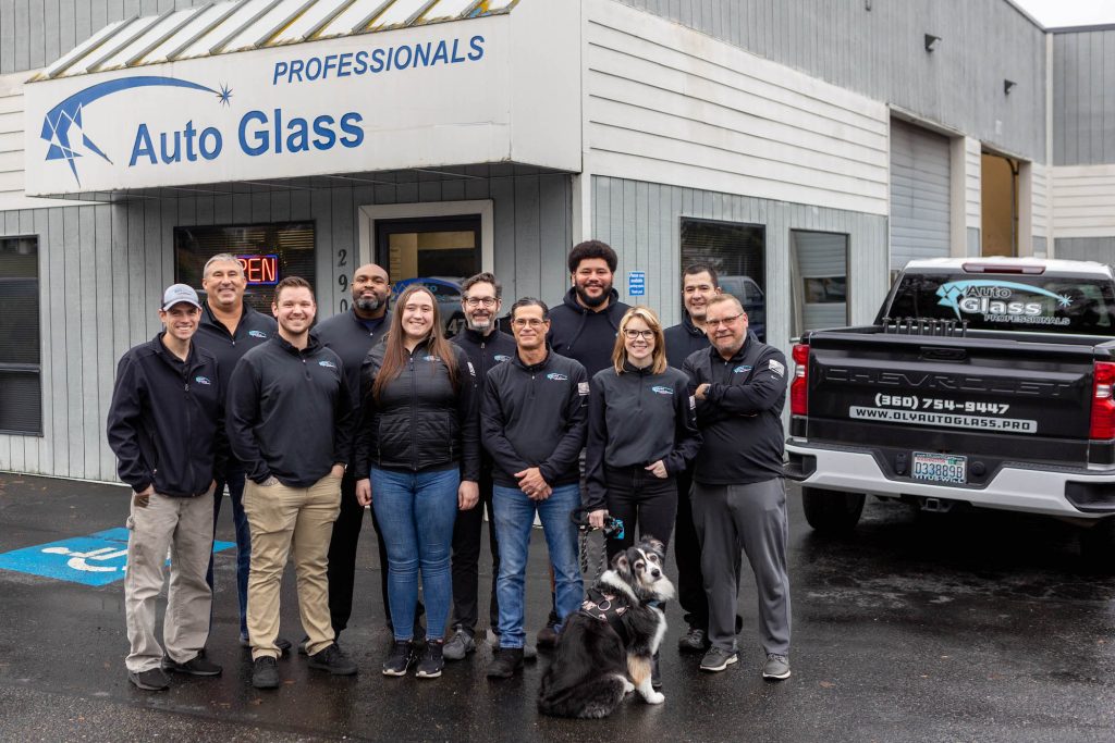 Auto Glass Professional staff including their dog, posing for a group photo outside Auto Glass Professionals in Olympla