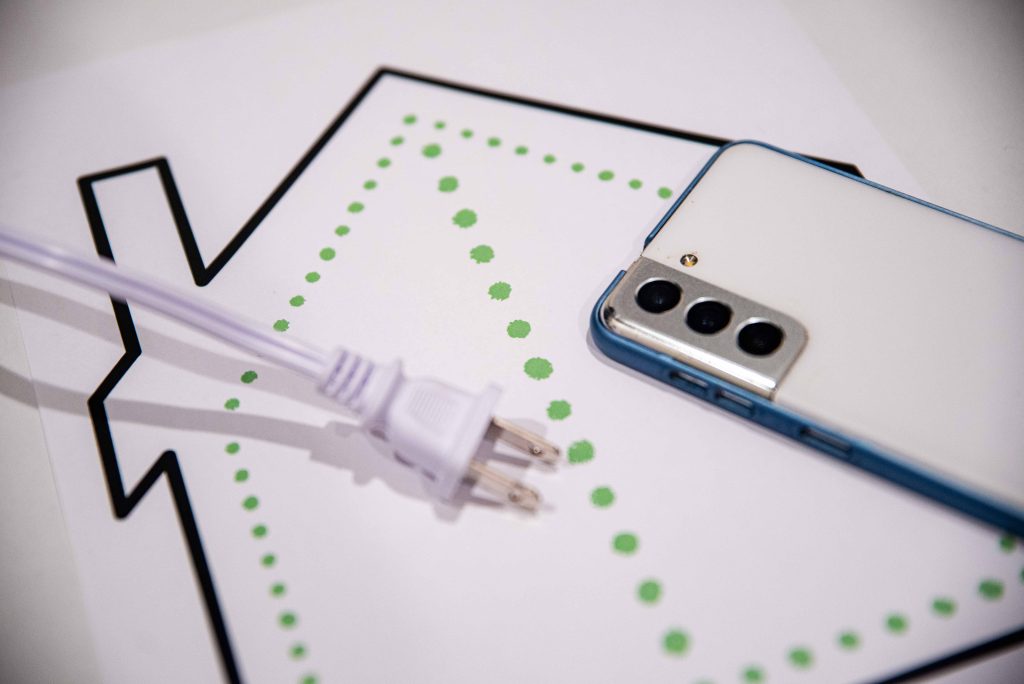 diagram of a house outline on a piece of a paper with a white cord and smartphone on it