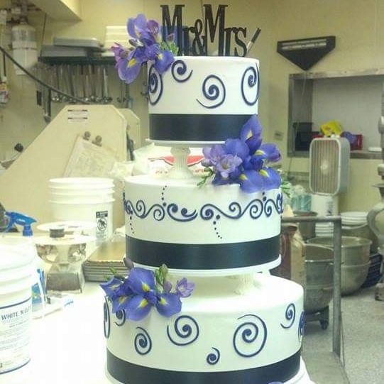 four-tiered white and black cake with purple flowers