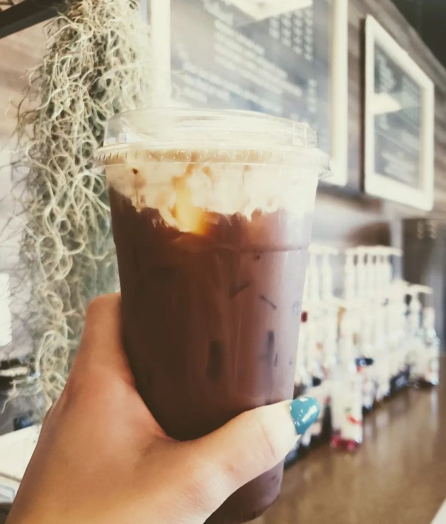 a hand holding an iced coffee drink up