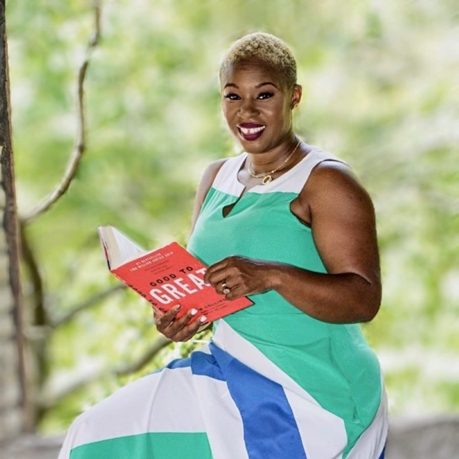 Jenefeness Franke sitting on a tree branch in a dress reading a book