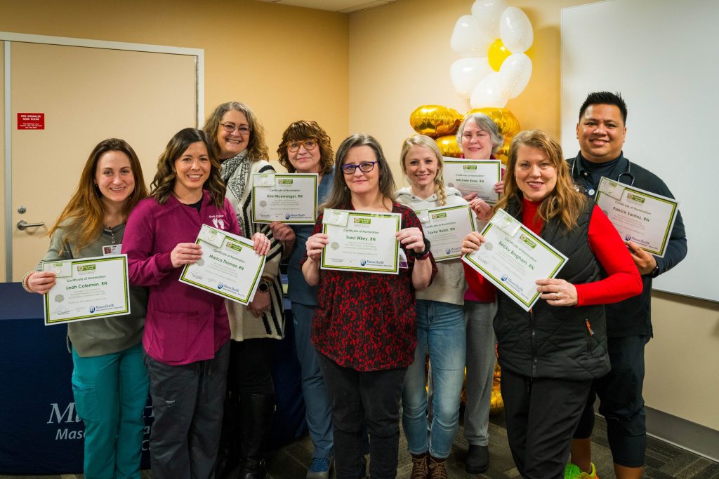 group of Mason Health employees posing for a photo holding paper award certificates