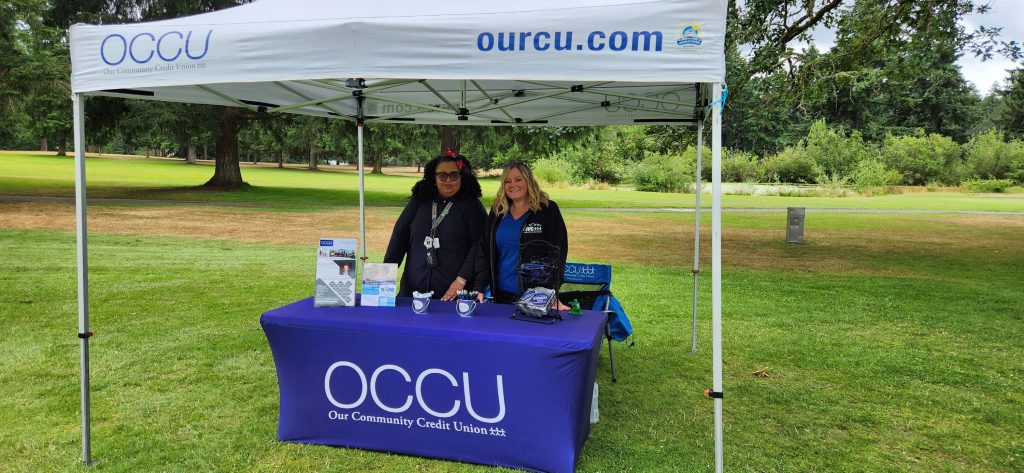 People at an Our Community Credit Union booth and pop up tent on a golf green