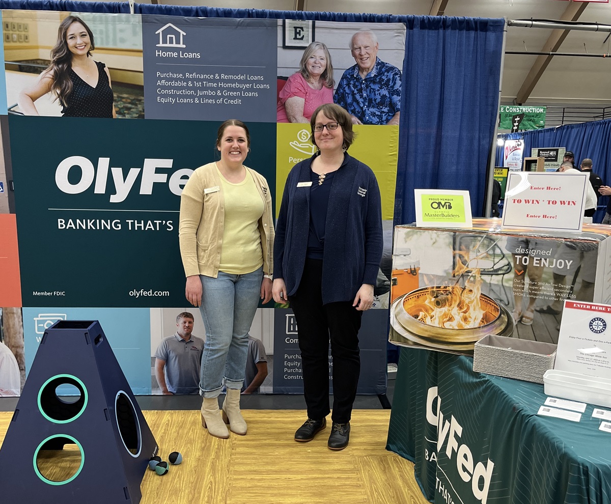 two OlyFed employees pose for a photo in their booth at the BIG Home & Remodel Show