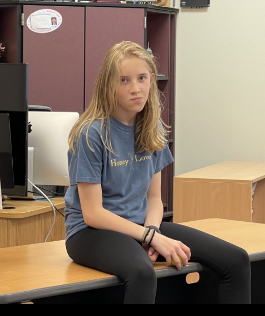 teenager sitting on a desk with a sour expression