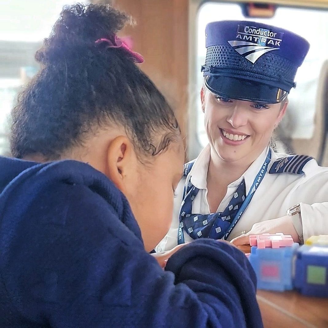Amtrak Cascades conductor stops to say hello to a child playing at a table on the train