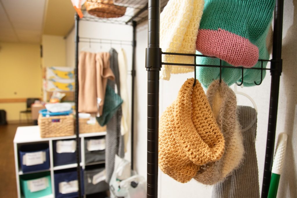 blankets and sweaters on a rack in a storage room