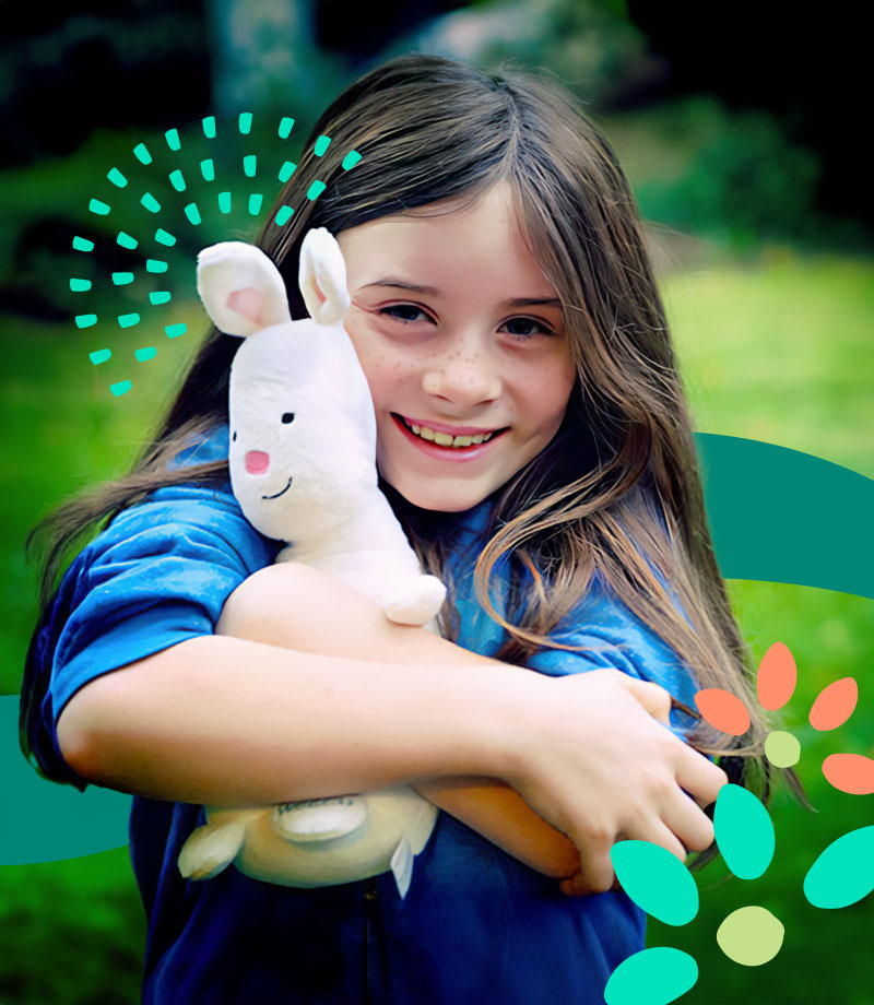 little girl hugging a white rabbit stuffed animal against a green background