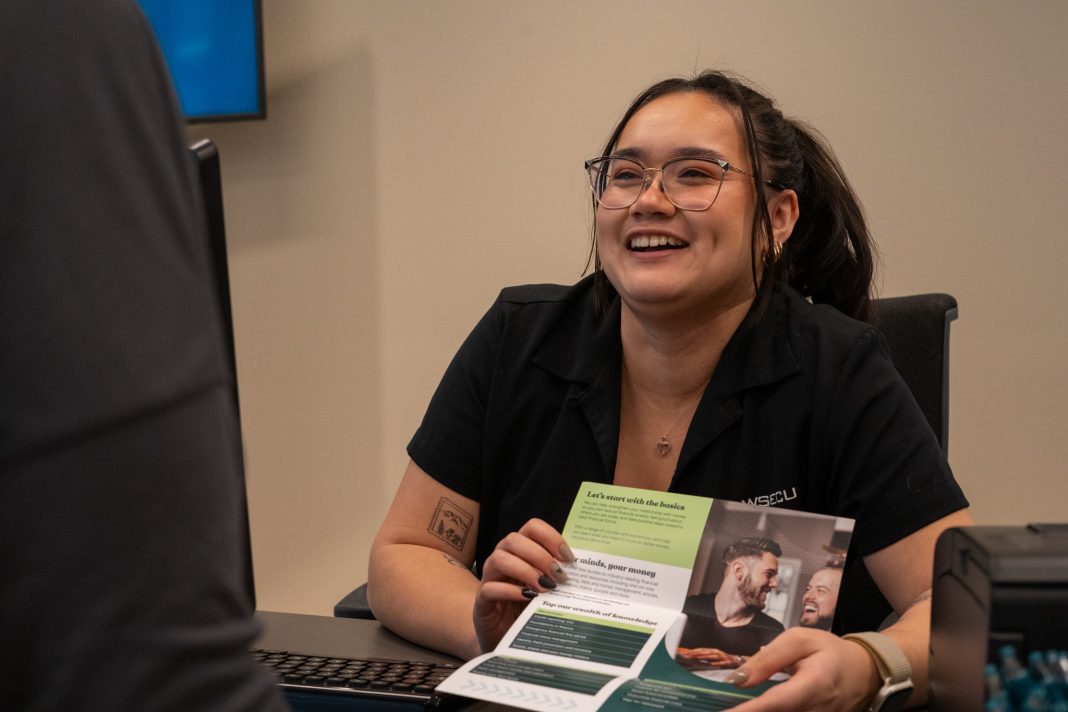 WSECU banker sitting at a desk showing a pamphlet to someone.