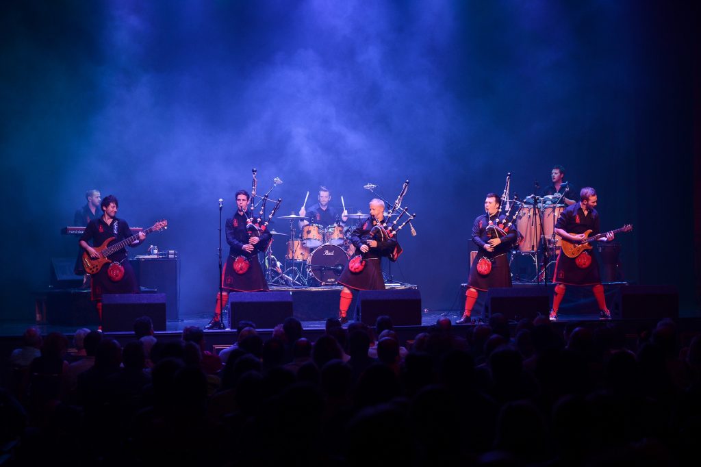 The Red Hot Chilli Pipers  performing on stage with smoke and lights